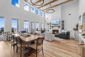 A spacious living area with a wooden dining table, striped sofas, and a fireplace. - Beautiful 4BR Beachfront | Elevator + Game Room (Port Bolivar)