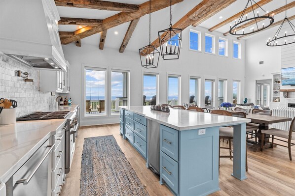 A spacious kitchen with a large island, wooden beams, and a view to the outside. - Beautiful 4BR Beachfront | Elevator + Game Room (Port Bolivar)