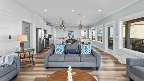 A spacious living area with a grey sofa, wooden coffee table, and a kitchen in the background. - Beachfront 5BR | Sleeps 16 | Fully Fenced Pet Friendly (Port Bolivar)