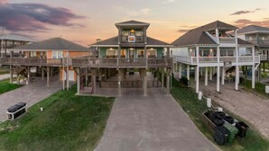 A beachfront hotel with multiple levels, a central tower, and a covered walkway. - Beachfront 5BR | Sleeps 16 | Fully Fenced Pet Friendly (Port Bolivar)