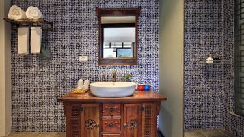 Casa de banho com lavatório, armário de madeira e azulejos estampados.