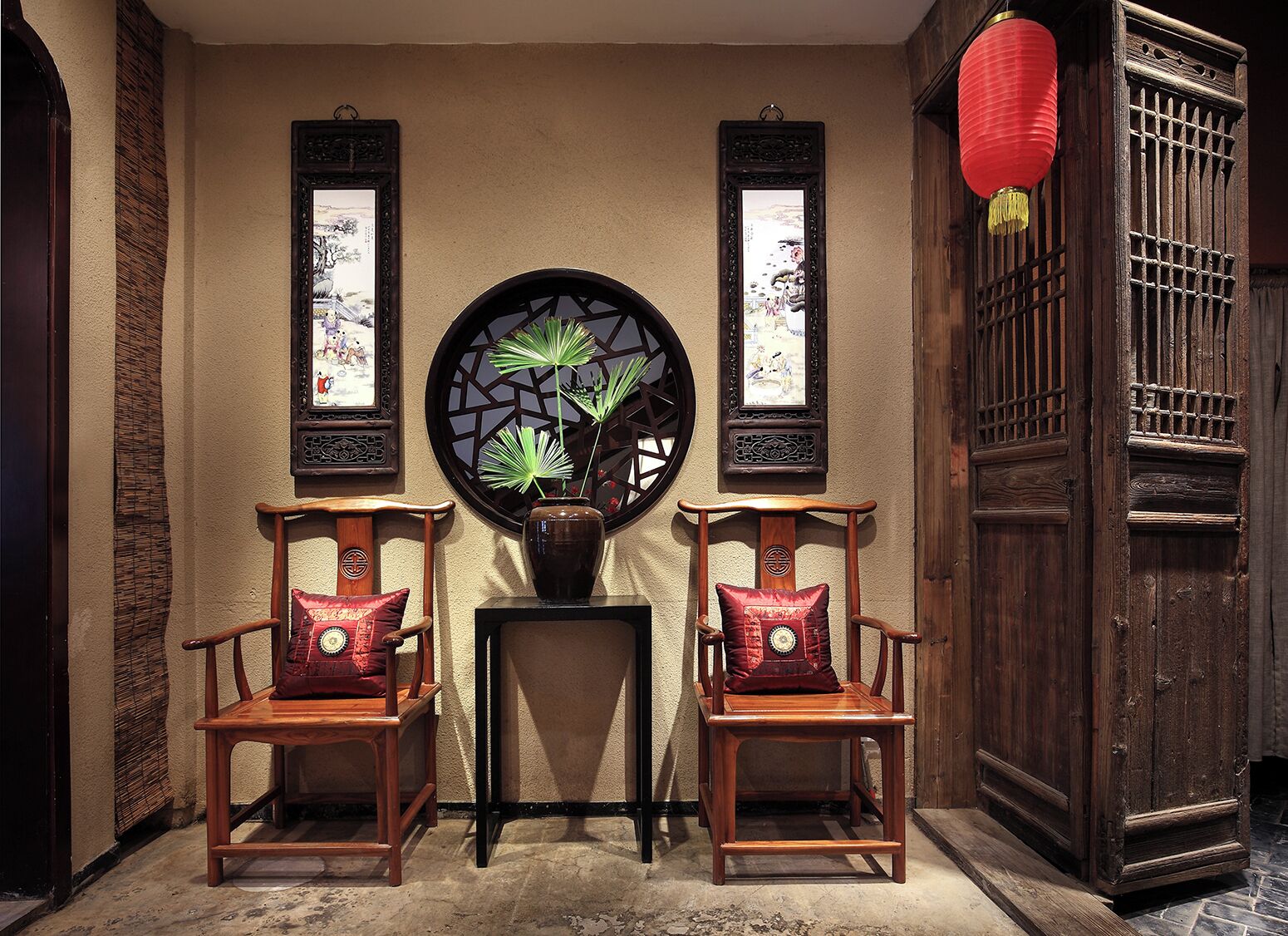 A traditional room with two wooden chairs, a small table, and a decorative wall piece.