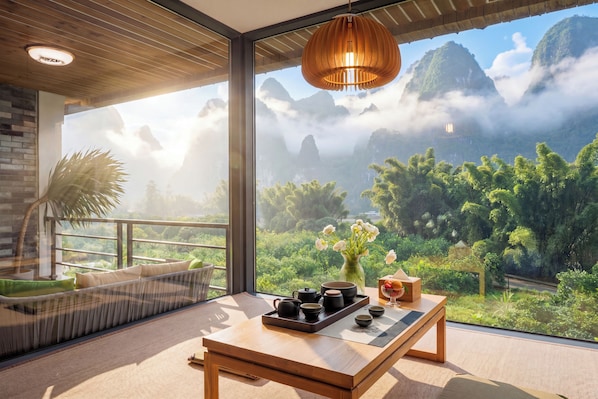 A modern room with a large window, a wooden table with tea set, and a hanging light fixture.
