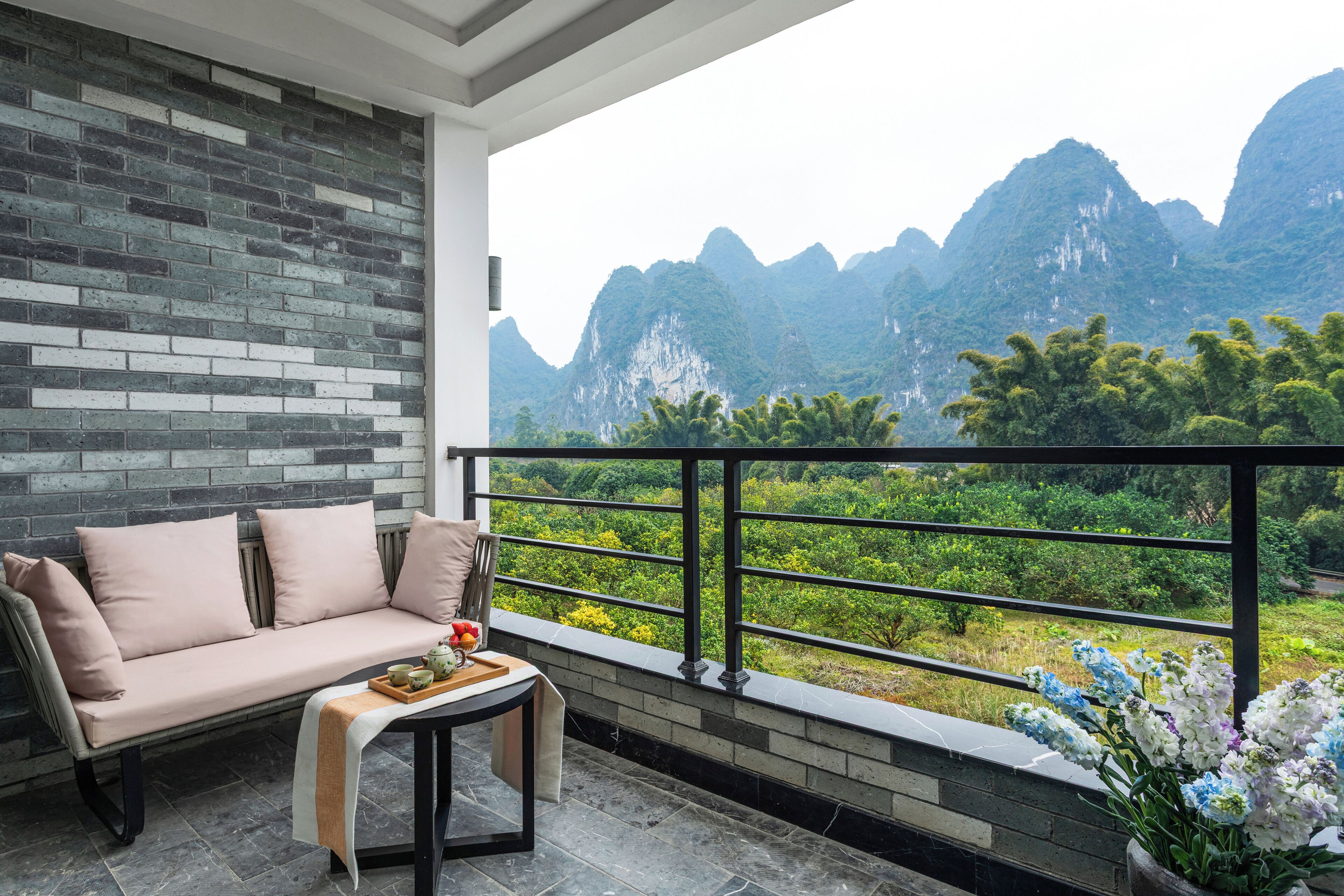 A balcony with a sofa, a small table, and a potted plant.