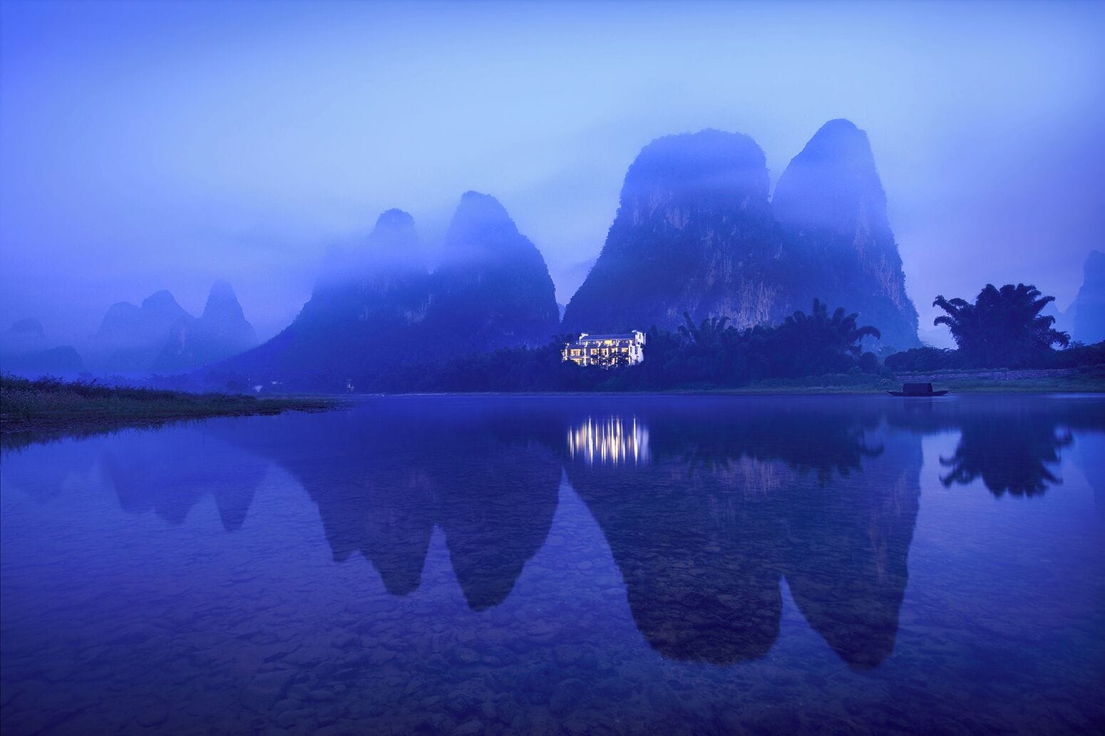 A calm lake with reflections of mountains and a building.
