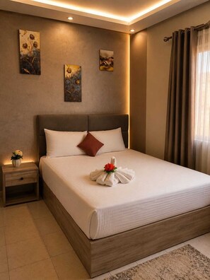 Una cama grande con cabecera de madera, una mesita de noche con un florero y una obra de arte en la pared.