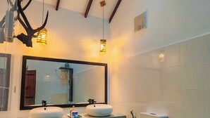 A modern bathroom with a dual sink vanity, a toilet, and a mirror.