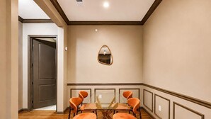 A conference room with a glass table and orange chairs, a mirror on the wall, and a door leading to another room. - Downtown Tulsa Apartment Near Arts District  Pool (Tulsa)