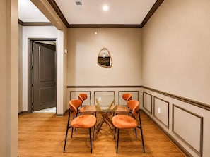 Una sala conferenze con tavolo in vetro e sedie arancioni, uno specchio a parete e una porta che dà su un'altra stanza.