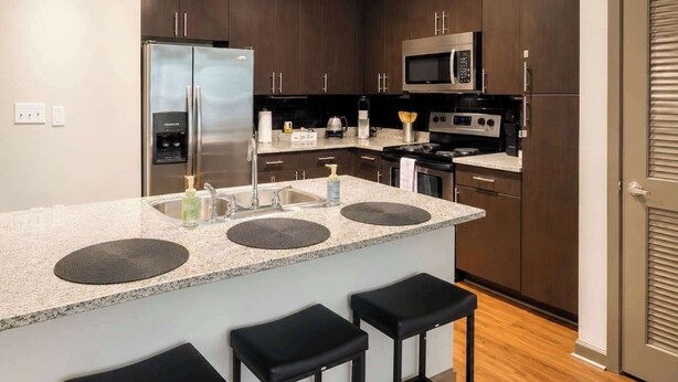 A modern kitchen with a central island, stainless steel appliances, and dark wood cabinets. - 2BR Modern Downtown Tulsa Stay Near BOK Center (Tulsa)