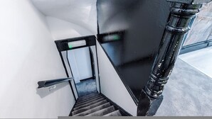 Una escalera con barandilla, una puerta y una tubería negra.