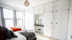 Ein modernes Schlafzimmer mit Bett, Schreibtisch, Stuhl und Kleiderschrank.