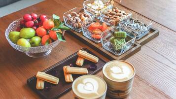 Ein Holztisch mit einer Schale Obst, einer Auswahl an Gebäck und zwei Tassen Kaffee.