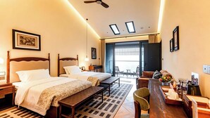 Quarto de hotel com duas camas, uma escrivaninha, uma cadeira, um ventilador de teto e vista para o exterior.