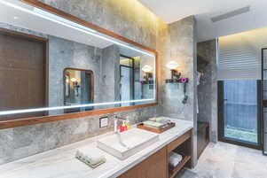 Un baño moderno con un espejo grande, un lavamanos blanco y un mueble de tocador de madera.