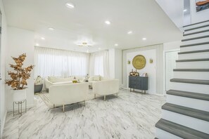 Ein modernes Wohnzimmer mit einer Sofagarnitur, einer Zimmerpflanze und einer Treppe.