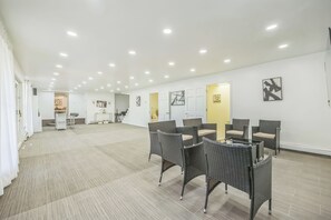 Ein geräumiges Zimmer mit Essbereich, weißen Wänden und Deckenleuchten.