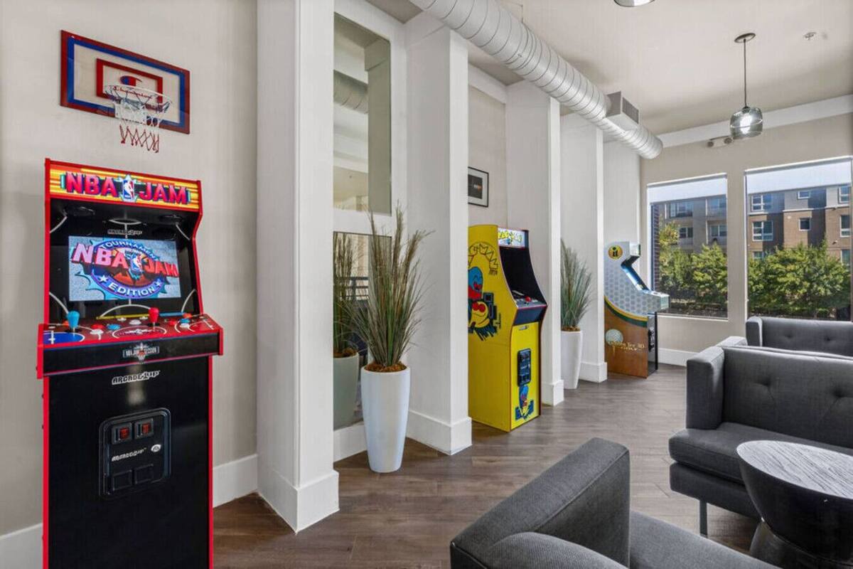 Espacio interior con juegos de arcade, asientos y ventanas amplias.