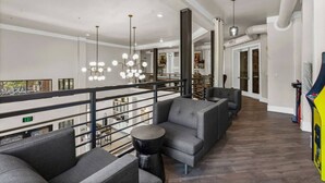 A spacious lounge area with a high ceiling, modern lighting fixtures, and a view of the interior. - AEA-Lake Carolyn TX (Irving)