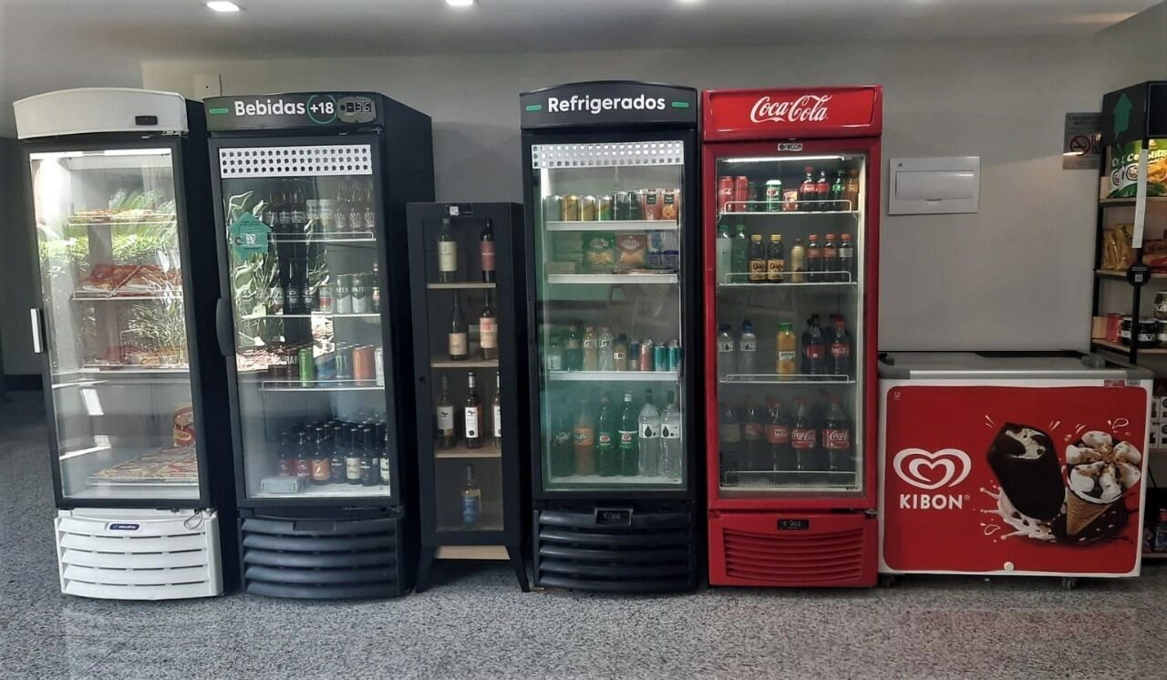 Cuatro máquinas expendedoras de bebidas con diferentes marcas y etiquetas.