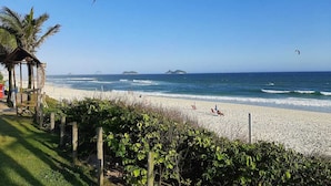 A beach with a wooden structure, a fence, and a clear view of the ocean and distant islands. - Beach access | Sea view | Kitchen | WiFi | Comfort (Rio de Janeiro)