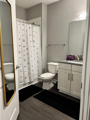 Ein Badezimmer mit Toilette, Duschvorhang und Waschtisch mit Spiegel.