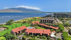 Ein Resort mit mehreren Gebäuden, einem Pool und Blick auf das Meer und ein Bergpanorama.