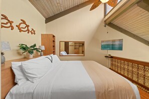 Ein Schlafzimmer mit einem Bett, einem Spiegel, einem Fernseher und einem hölzernen Kopfteil.