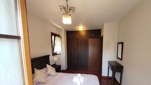 Ein Schlafzimmer mit Bett, Nachttisch, Schreibtisch, Spiegel und Tür.