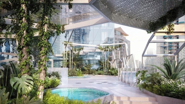 En moderne bygning med swimmingpool på taget, omgivet af frodig beplantning og en glasfacade.