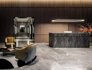 Eine moderne Lobby mit einer Rezeption, einer Sitzecke mit Sofa und Sessel, sowie einem Korridor zu anderen Bereichen des Gebäudes.