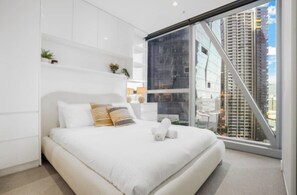 Ein modernes Schlafzimmer mit einem großen Bett, Blick auf die Stadt und einer Glaswand.