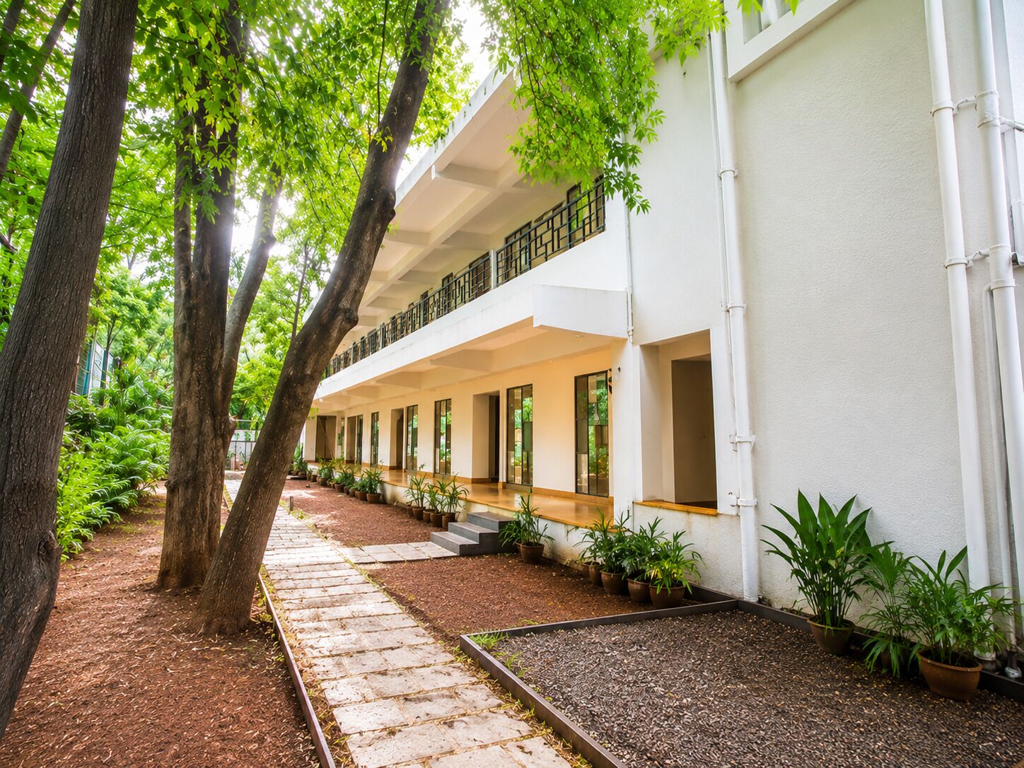 Un bâtiment doté d’un espace extérieur abrité, de plantes en pot et d’un chemin.