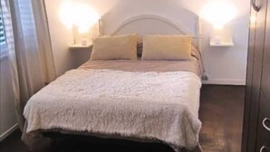 Une chambre à coucher avec un lit, des lampes de chevet, un lustre et une armoire.