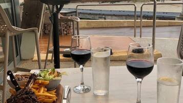 A table with a meal, including steak, fries, and salad, and two glasses of red wine.