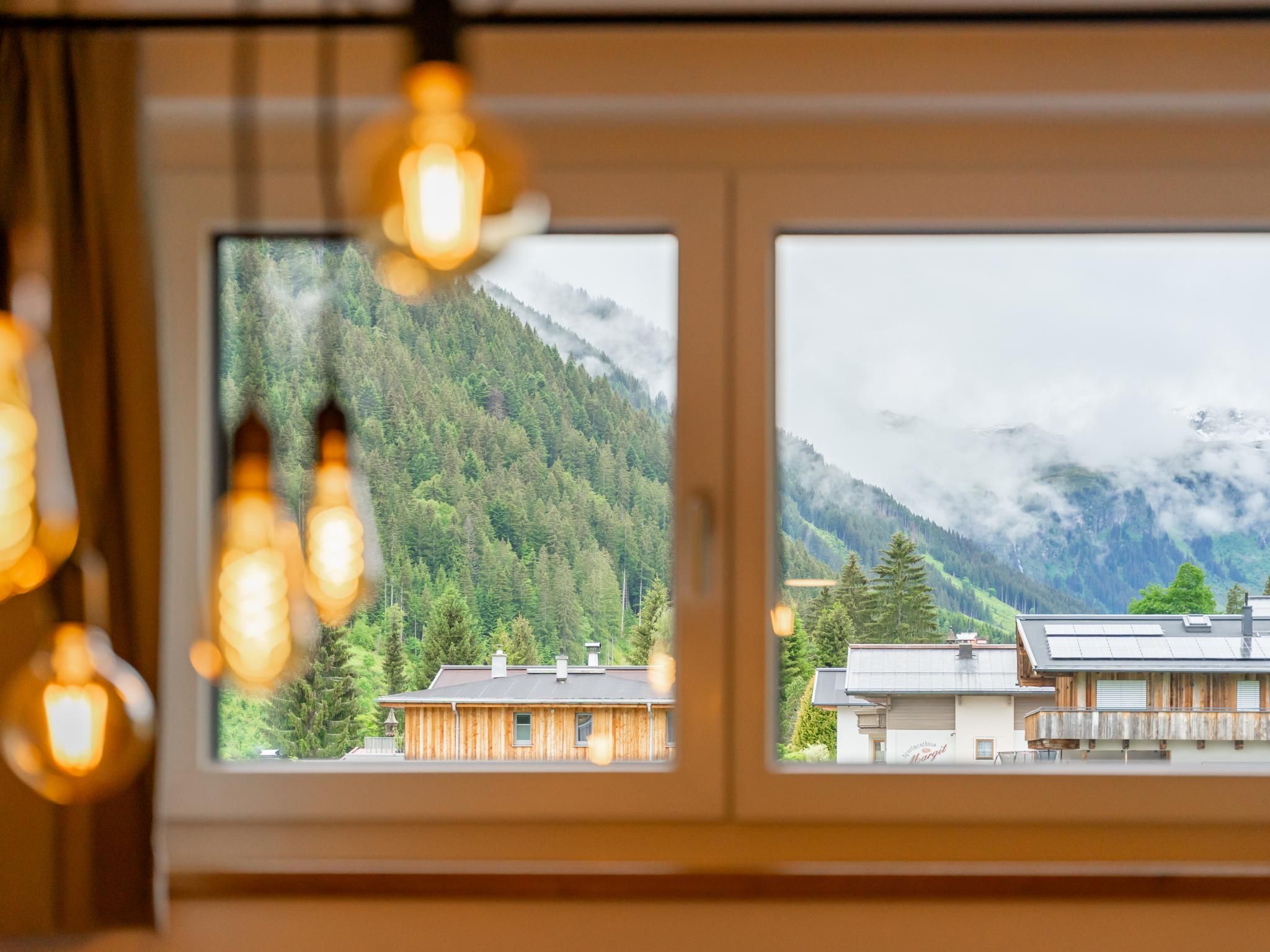 A window with two views: a forested mountain and a building with solar panels.