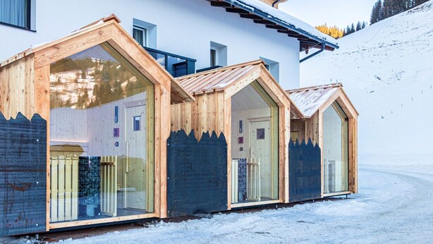 A modern building with large glass windows and wooden structures. - Ski-in, ski-out in Alpine style and sauna (Hinterglemm)