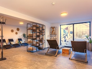 A spacious room with a large window, a metal shelf with towels, two wicker chairs, and a massage chair. - Ski-in, ski-out in Alpine style and sauna (Hinterglemm)