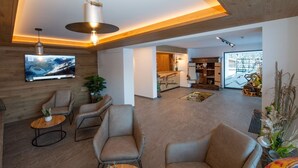 A modern interior with a TV, seating, and a kitchen area. - Ski-in, ski-out in Alpine style and sauna (Hinterglemm)