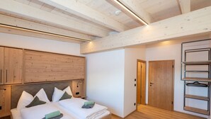 A bedroom with a wooden bed, a wardrobe, and a door leading to another room. - Ski-in, ski-out in Alpine style and sauna (Hinterglemm)