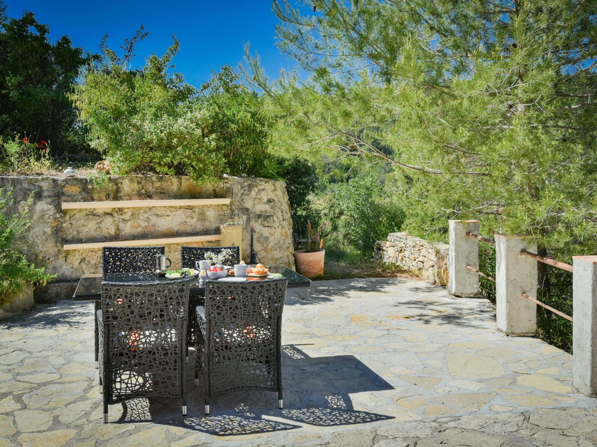 Un área de comedor al aire libre con suelo de piedra, una pared de piedra y una valla de madera.