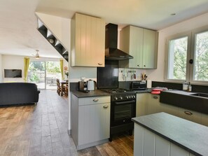Eine moderne Küche mit Einbauherd, Backofen und Mikrowelle. Es gibt einen Essbereich mit Tisch und Stühlen sowie eine Treppe zu einer oberen Ebene.