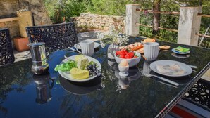 An outdoor dining table with plates of food, a pitcher, and a vase of flowers. - Lovely little house for two nestled in nature (Flayosc)