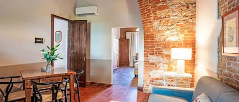 A cozy living area with a brick wall, a dining table with chairs, a sofa, and a lamp.