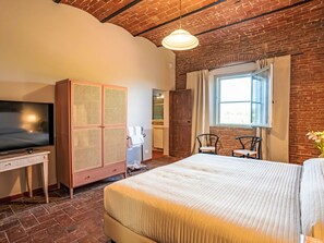 A hotel room with a large bed, a television, a wardrobe, a desk, and a window with curtains. - Apartment Madia by Interhome (Grosseto)