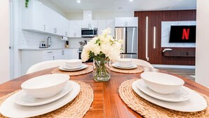 A modern kitchen with white cabinets, a stainless steel refrigerator, a microwave, and a flat-screen TV displaying the Netflix logo. - Entire Spacious Luxury Retreat Near DT | Sleeps 4 | Fast Wifi | Free Parking (Calgary)