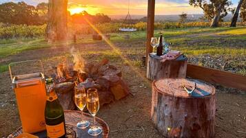 An outdoor dining setup with a bottle of wine, glasses, and a portable cooler.