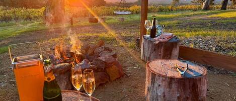 An outdoor dining setup with a bottle of wine, glasses, and a portable cooler.