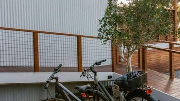 A bicycle parked next to a building with a metal fence and a tree in the background.