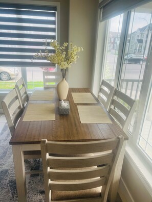 A dining table with chairs, a vase with flowers, and a tissue box. - Beautiful, Modren family house 5 min from airport near busstop,resturants,Malls (Calgary)